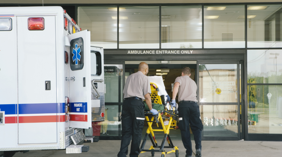 Paramedics taking patient on stretcher from ambulance to hospital.