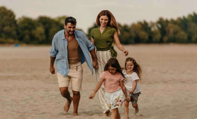 Happy parents are having fun with their two little girls on the beach.