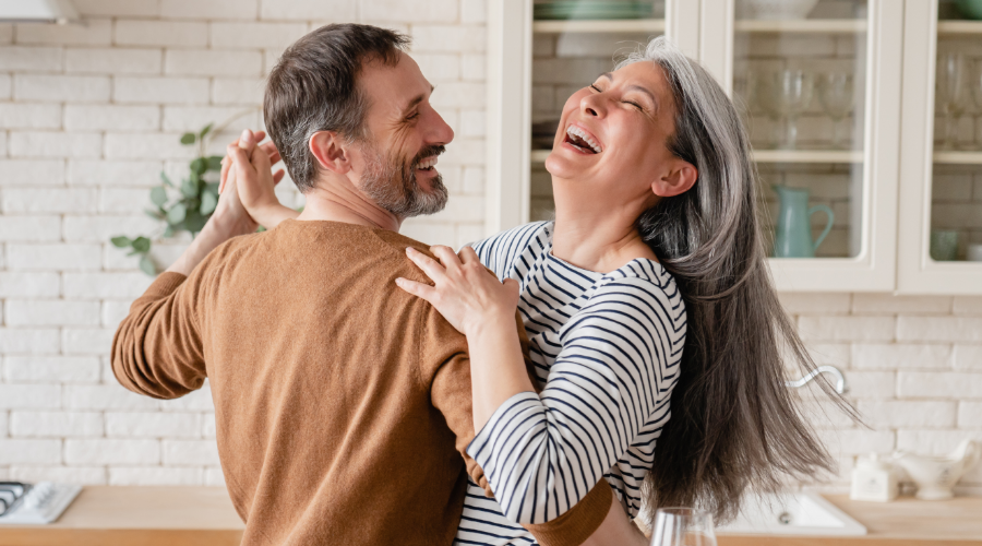 A couple joyfully dancing in the kitchen, celebrating life and health, feeling supported by their Civic Health Savings Account.