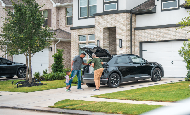 A family carrying bags from their car into the house—everyday moments protected with home and auto insurance through TruStage.