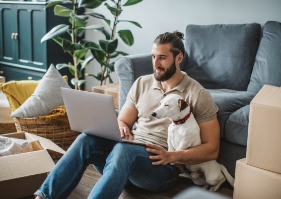 A man reads about adjustable-rate mortgage loans on the website while sitting in his living room, with his dog.