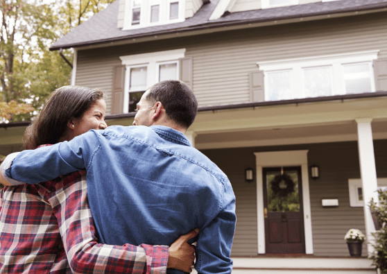 Wrapped in each other’s arms, a couples walks toward the house they financed with a fixed-rate mortgage loan.