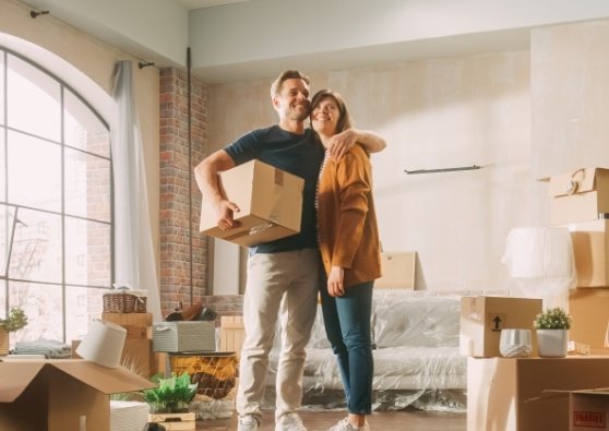Surrounded by boxes, a couple is excited to finally move in after closing on a First-time Homebuyer mortgage loan.