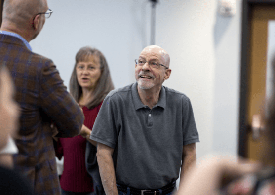 Man smiling while speaking to another man