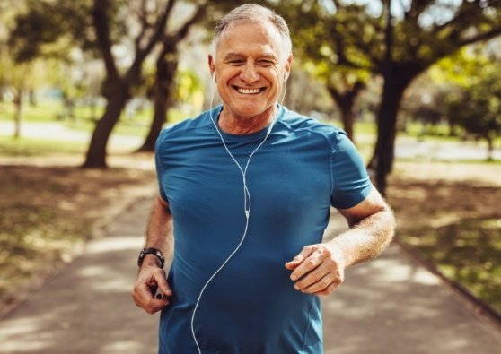 Older gentleman jogging in the park while listening to music.