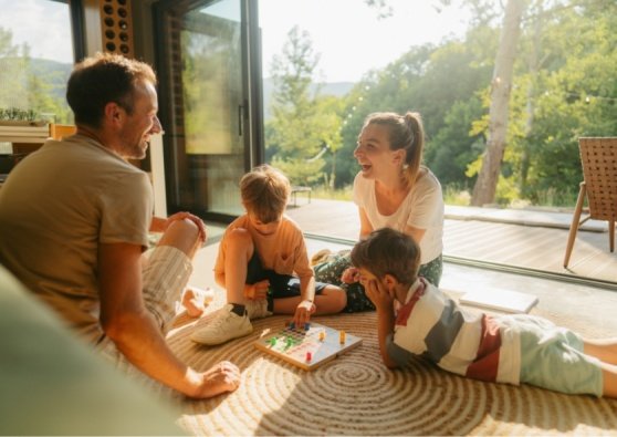 Family of four, playing a board game on the floor.
