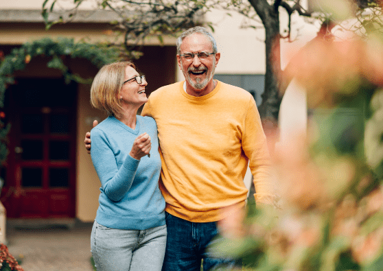 Retired couple walking and laughing, while enjoying the outdoors.