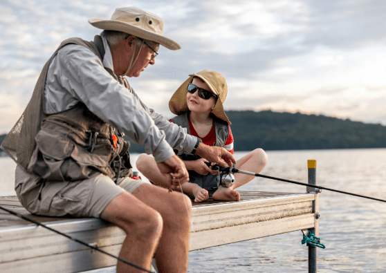 Retired grandfather teaching his grand son how to fish off a pier. 