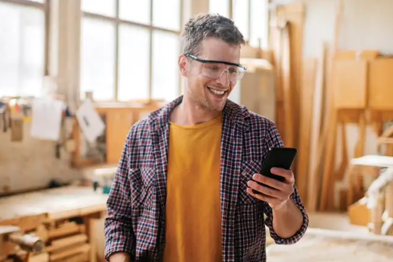 Owner of a woodworking studio smiling after checking on his rewards in the Civic mobile app.