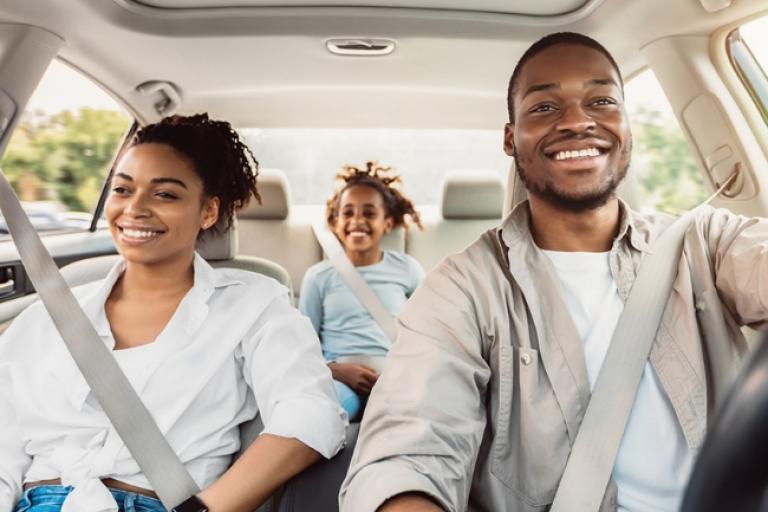 A family driving away in a new car thanks to their GAP+ insurance coverage.