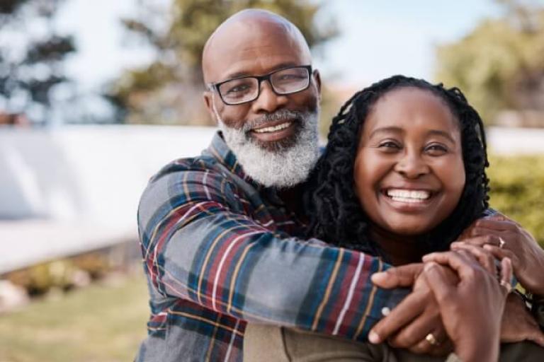 Happy couple hugging in their backyard, excited about using their home equity to make their goals a reality.