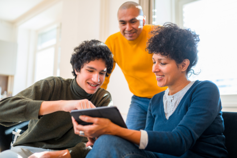 Parents showing their teen how to access his NexGen Checking account on his tablet. 