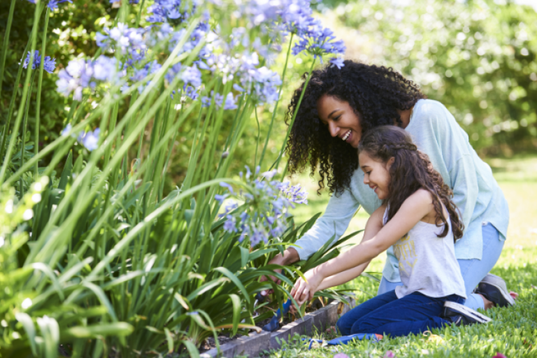 A mother and her daughter planting flowers in the garden.