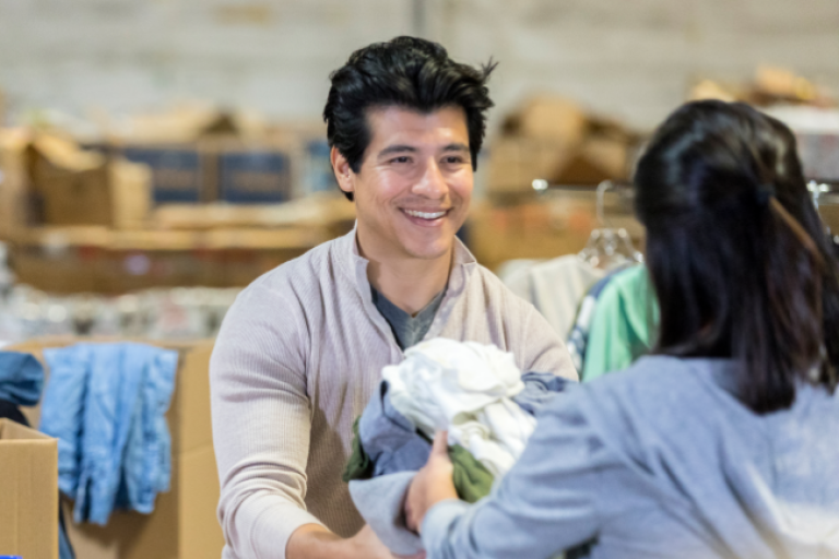 A man handing out clothes at a drive, efficiently managing donations with the support of a Civic Nonprofit Checking Account.