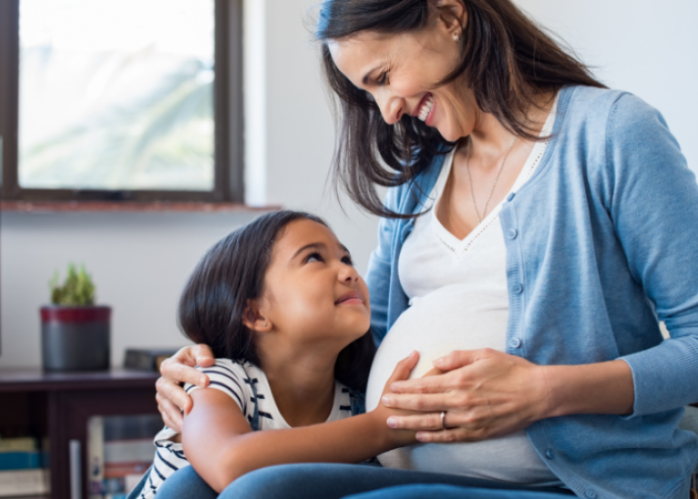 An expecting mom sits with her young daughter, gently embracing her growing belly, feeling comforted by the security of her Civic Personal Line of Credit Loan as she prepares for the future.