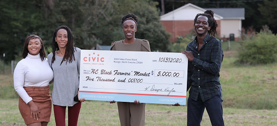 three women and one male holding a giant check